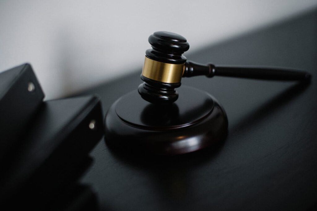 High angle of shiny wooden ceremonial mallet with golden detail placed on judge tale near documents folders